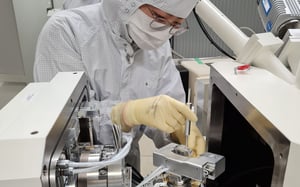 Technician in cleanroom suit installing FT-NMT04 nanoindenter in a SEM.